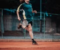 Split Croatia September 2020 Man playing tennis seen sprinting to catch the ball served short. Playing at night on an orange clay