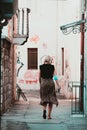 Split Croatia September 2020 Rear view of a woman walking along a narrow grafitti filled street in Split, wearing a facemask along Royalty Free Stock Photo