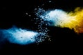 Split debris of stone exploding with blue powder against black background