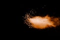 Split debris of stone exploding with orange powder against black background