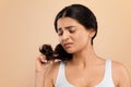 Split Ends. Upset indian woman looking at her damaged hair Royalty Free Stock Photo