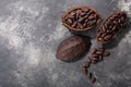 Split fermented cocoa pod with shelled cacao beans atop dark grey backdrop, top view