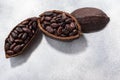 Split fermented cocoa pod with shelled cacao beans atop light grey backdrop, top view, copy space