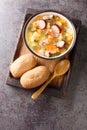 Split pea soup with potato, onion, carrot, bacon and sausages close-up in a bowl. Vertical top view Royalty Free Stock Photo