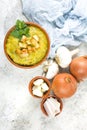 Split pea soup in rustic bowl decorated with fresh green leaves, garlic, onion and slices of lard Royalty Free Stock Photo