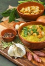 Split pea soup in rustic bowl decorated with fresh green leaves, garlic, onion and slices of lard Royalty Free Stock Photo