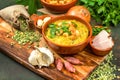 Split pea soup in rustic bowl decorated with fresh green leaves, garlic, onion and slices of lard Royalty Free Stock Photo