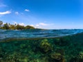 Split photo with tropical island and coral reef. Clear blue sky and underwater view. Royalty Free Stock Photo