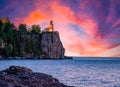 Split Rock lighthouse at the edge of a waterside cliff under the orange and blue shaded sunset sky Royalty Free Stock Photo