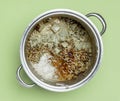 Spoiled food in a steel pot, isolated on green mold color background. Top view. Food spoilage. Royalty Free Stock Photo