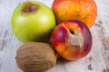 Spoiled kiwi, peach and apple on old wooden white table