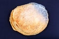 Spoiled moldy pancake, food gone bad concept. Fungal mold spores growing on round pastry surface on dark background