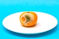 Spoiled rotten mandarin on white plate on blue background