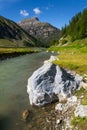 Spol River flowing in Lake Livigno, Corno Brusadella Mountain background