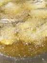 Sponge the boiling oil on the pan. Close-up of fish pieces in old boiling oil with lots of bubbles in a pan of street food in a