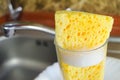 Sponge with foam for washing dishes in glass on the sink at the kitchen, close up. Royalty Free Stock Photo