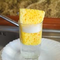 Sponge with foam for washing dishes in glass on the sink at the kitchen. Royalty Free Stock Photo