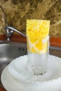 Sponge with foam for washing dishes in glass on the sink at the kitchen. Royalty Free Stock Photo