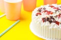 Sponge layer birthday cake with whipped cream frosting chocolate star sprinkles strawberry jam. Pink paper drinking cups party Royalty Free Stock Photo