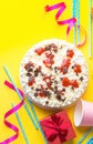 Sponge layer birthday cake with whipped cream frosting milk chocolate star sprinkles strawberry jam. Pink paper drinking cups Royalty Free Stock Photo