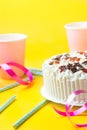 Sponge layer birthday cake with whipped cream frosting chocolate star sprinkles strawberry confiture. Pink paper drinking cups Royalty Free Stock Photo