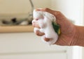 Sponge in squeeze hand with dishwashing liquid