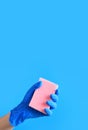 Sponge for washing dishes in a female hand on a blue background Royalty Free Stock Photo