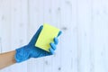 Sponge for washing dishes in a female hand on a light wood background Royalty Free Stock Photo