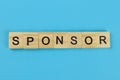 Sponsor word of wooden letters on a blue background