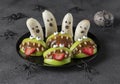 Spooky banana ghosts monsters and green apple monsters for Halloween party on gray background decorated with spiders