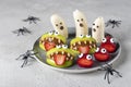 Spooky banana ghosts monsters, strawberry and green apple monsters for Halloween party on light gray background