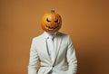 Spooky businessman wearing a carved pumpkin mask.