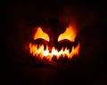 Spooky carved Jack o Lantern glowing a fiery red with thick smoke poring out of the face with a scary evil grin
