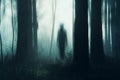 A spooky concept of a ghostly figure silhouetted between trees in a forest on a moody, foggy winters day. With a grunge, abstract Royalty Free Stock Photo