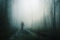 A spooky concept of a hiker with a rucksack walking on a path through a spooky forest on a moody, foggy winters day. With a grunge Royalty Free Stock Photo