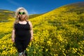 Spooky, creepy blonde woman wearing green alien sunglasses in a field of goldfield wildflowers in Carrizo Plain National Monument