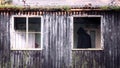 A spooky creepy hooded figure. Back to camera in an abandoned building. Framed by a window