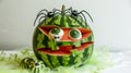 Spooky Delights: Hauntingly Cved Watermelon with Eerie Eyes and Creepy Spiders on a White Backdrop Royalty Free Stock Photo