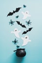 Spooky evil spirits and witch pot on blue background. Flat lay, top view spiders, paper ghosts, bats