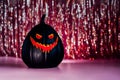 Spooky halloween black pumpkin, Jack O Lantern, with red illuminated evil face and eyes on shining tinsel curtain on the Royalty Free Stock Photo