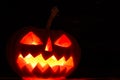 Spooky Halloween pumpkin jack-o-lantern with burning candles on dark background Royalty Free Stock Photo