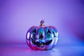 Spooky halloween pumpkin, Jack O Lantern, with an evil face and eyes made with holographic glass in neon lighting on