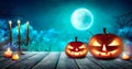 Spooky Halloween pumpkins, Jack O Lantern, with an evil face and eyes on a wooden table with a misty dark background and full moon Royalty Free Stock Photo