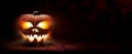 The spooky haunted evil glowing eyes of Jack O' Lanterns, halloween pumpkin, on the right of a wooden bench