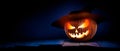 The spooky haunted evil glowing eyes of Jack O' Lanterns, halloween pumpkin, on the right of a wooden bench