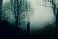 A spooky hooded figure standing in a forest. With a blurred, glitch abstract edit Royalty Free Stock Photo