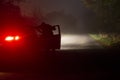 A spooky, mysterious hooded figure, looking into a car with the door open. On a foggy country road in winter at night