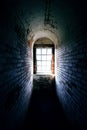 Spooky narrow old brick corridor with light shining through a window at the end Royalty Free Stock Photo