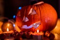 Spooky smiling halloween pumpkin in burning fire candles flames.