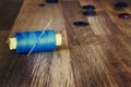 Spool of blue sewing thread with a needle and buttons on wooden background. Royalty Free Stock Photo